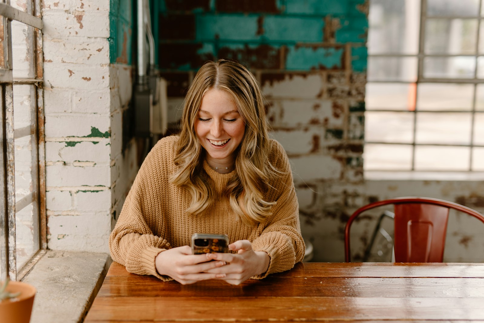 A smiling woman reading her phone at a café table